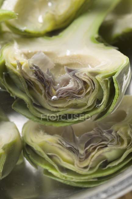 Varias mitades de alcachofa en bandeja - foto de stock