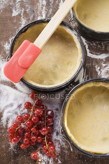 Boîtes de cuisson tapissées de pâte et de groseilles rouges — Photo de stock