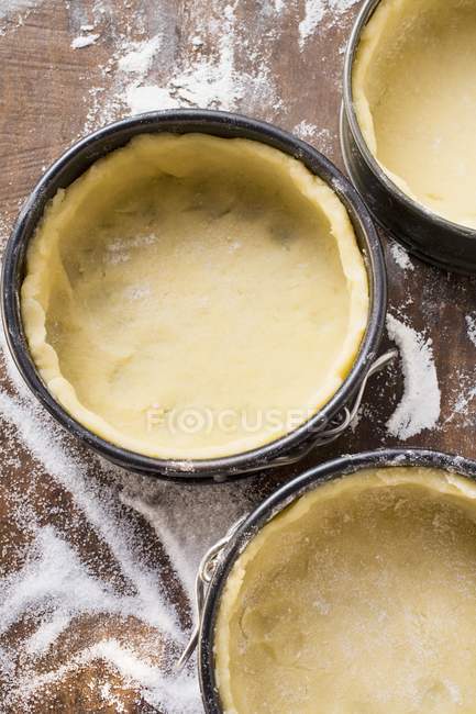 Closeup top view of baking tins lined with raw pastry — Stock Photo