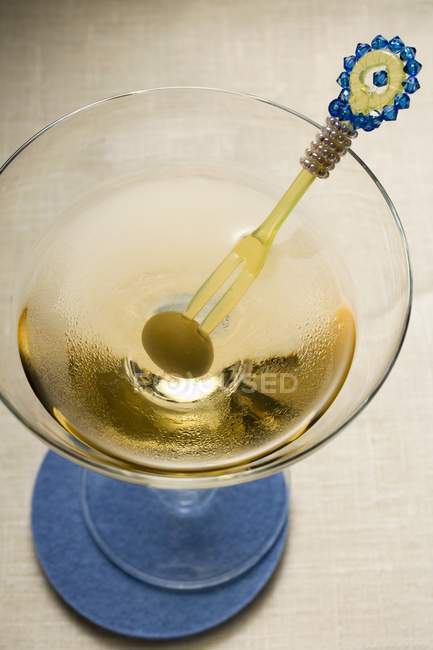 Martini with green olive on cocktail fork — Stock Photo