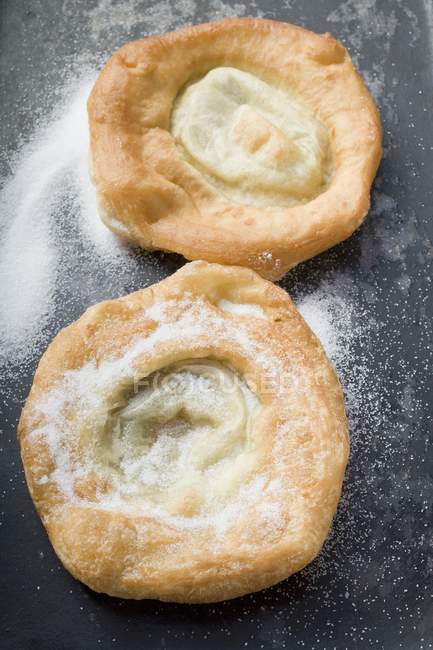 Closeup view of two Auszogene Bavarian fried pastries with icing sugar — Stock Photo