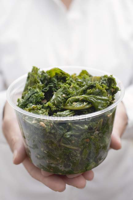 Woman holding cooked kale — Stock Photo