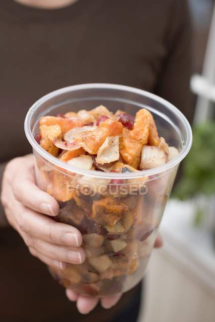 Closeup view of woman holding vegetable dish in plastic tub — Stock Photo