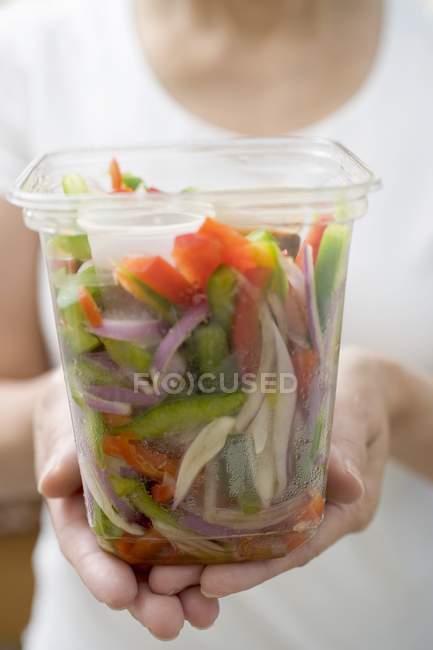 Женщина держит пластиковый контейнер с овощами, живот — стоковое фото