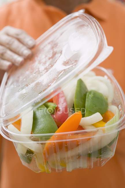 Frau hält Plastikbehälter mit Gemüse — Stockfoto