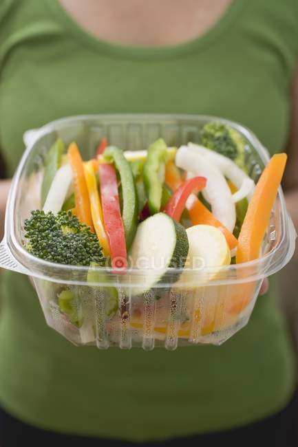 Mulher segurando recipiente de plástico de legumes fatiados em mãos, parte central — Fotografia de Stock