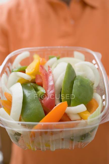 Woman holding plastic container of vegetables in hands, midsection — Stock Photo