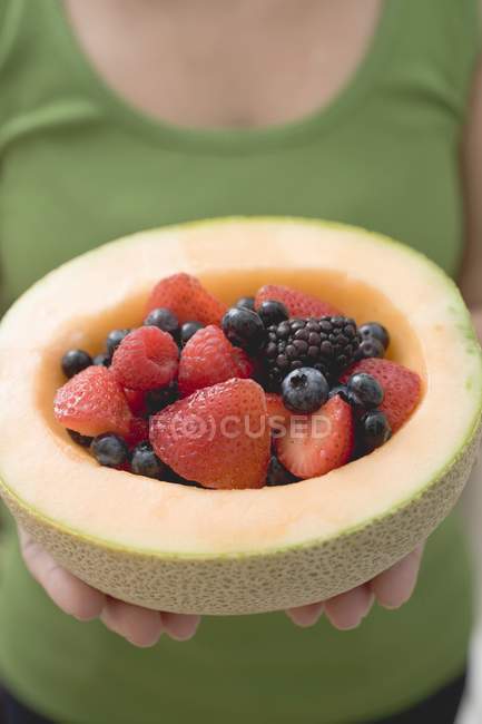 Woman holding fresh berries in melon — Stock Photo
