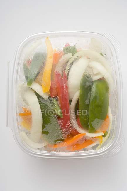 Legumes fatiados em recipiente de plástico sobre fundo branco — Fotografia de Stock