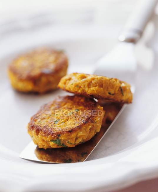 Closeup view of carrot Patties on spatula and white dish — Stock Photo