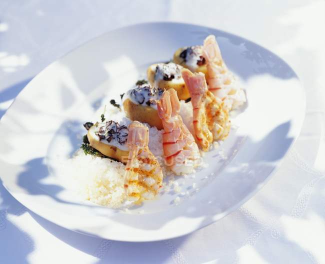 Scampi alla griglia con patate su sale marino su piatto bianco — Foto stock