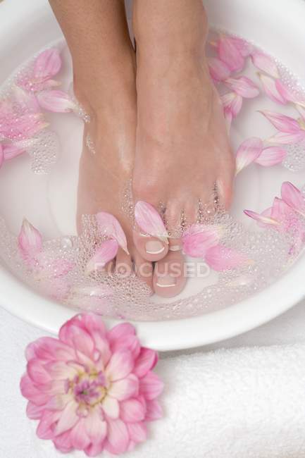 Жінка, насолоджуючись заспокійливою ванною з квіткових пелюсток — стокове фото