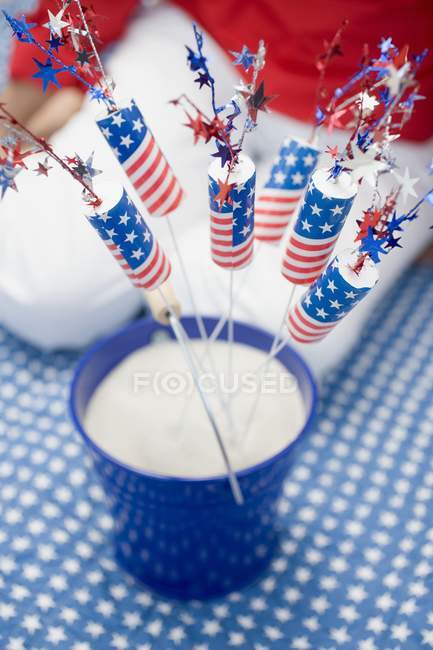 Closeup view of sparklers in bucket of sand with seated woman on background — Stock Photo