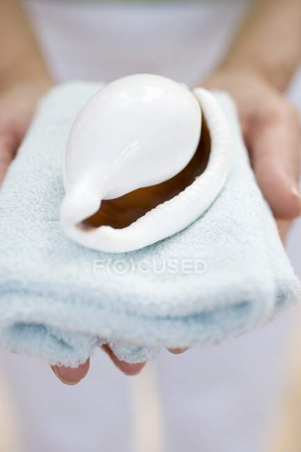 Closeup view of woman holding shell on towel — Stock Photo