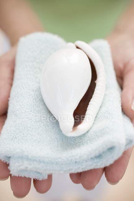 Closeup view of woman holding shell on towel — Stock Photo