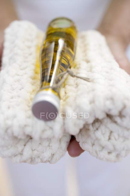 Mulher segurando garrafa de óleo corporal na toalha — Fotografia de Stock
