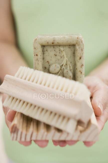 Mujer sosteniendo jabón de oliva, jabonera y cepillo - foto de stock