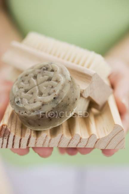 Woman holding olive soap, soap dish and brush — Stock Photo