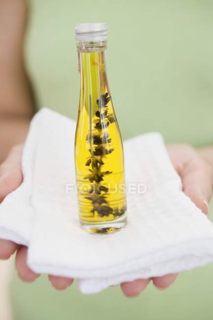 Woman holding bottle of body oil on towel — Stock Photo