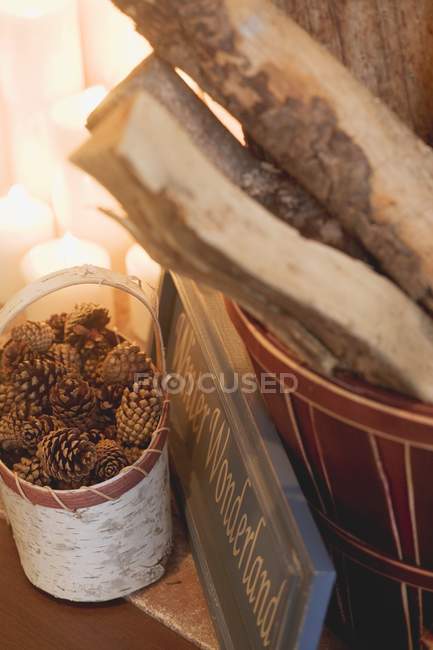 Erhöhter Blick auf Baumstämme und Zapfen in Körben mit brennenden Kerzen und Schild mit Winterwunderland-Worten — Stockfoto
