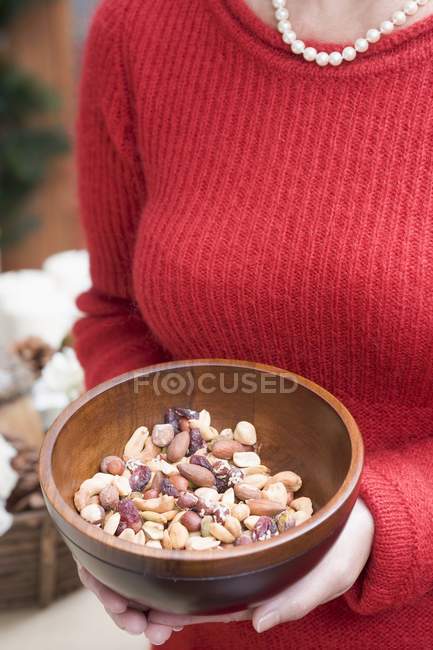 Cropped view of woman holding wooden bowl of nuts — Stock Photo