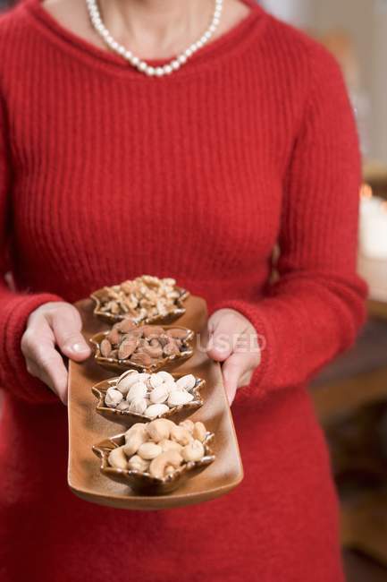 Woman holding dishes of nuts — Stock Photo