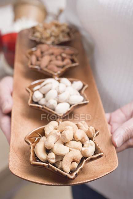 Woman holding dishes of nuts — Stock Photo