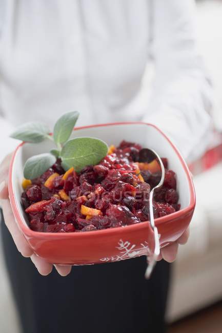 Closeup cropped view of woman holding dish of cranberry sauce — Stock Photo