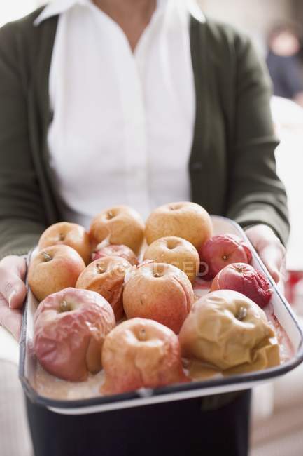 Woman holding baked apples — Stock Photo