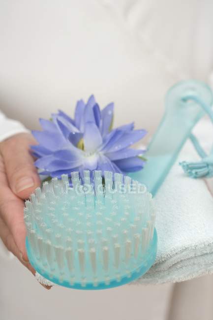 Cropped view of hands holding brush, water lily and towel — Stock Photo