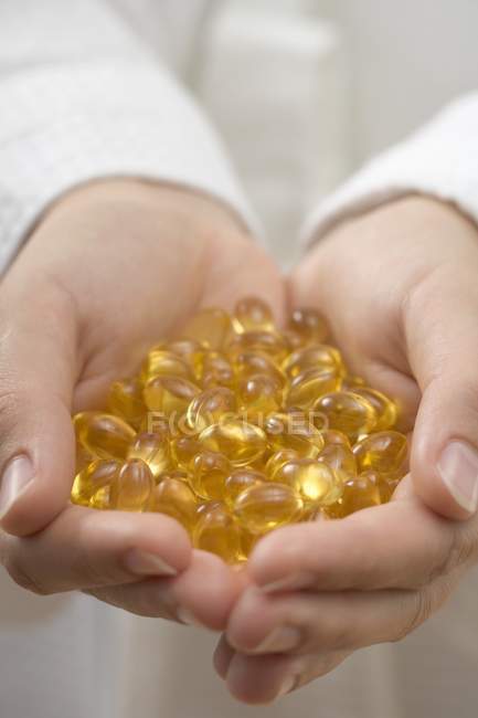 Vista close-up de mãos segurando cápsulas de vitamina — Fotografia de Stock