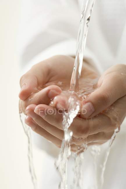 Cupped female hands under running water — Stock Photo