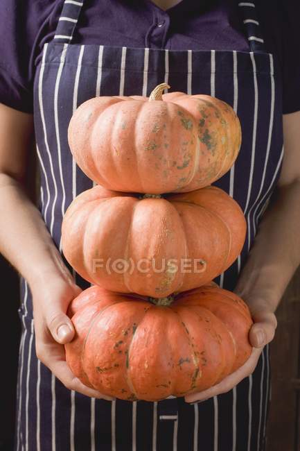 Woman holding heap of pumpkins — Stock Photo