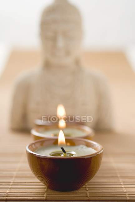 Tealights frente a la estatua de Buda - foto de stock