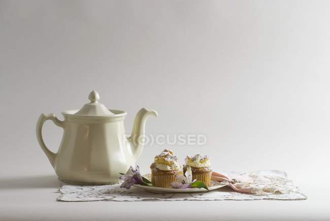 Тарелка кексов с чайником — стоковое фото