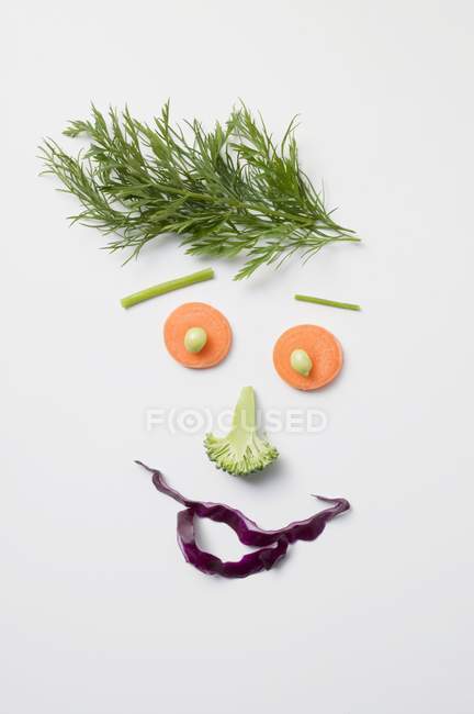 Visage amusant à base de légumes et d'aneth sur une surface blanche — Photo de stock