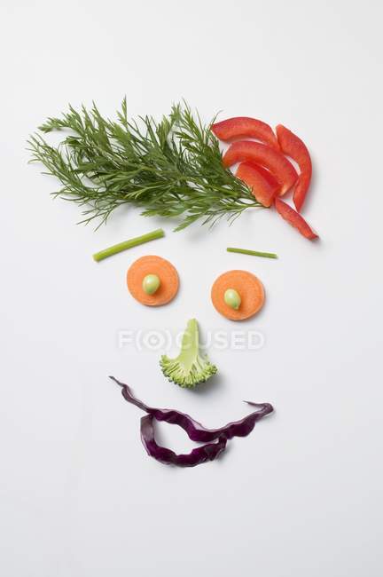 Cara divertida hecha de verduras y eneldo sobre la superficie blanca - foto de stock