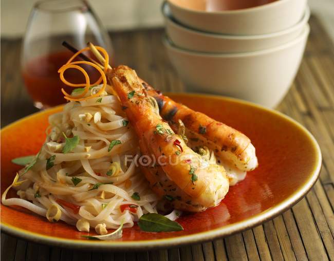 Vue rapprochée des crevettes thaïlandaises avec des nouilles sur plaque orange — Photo de stock