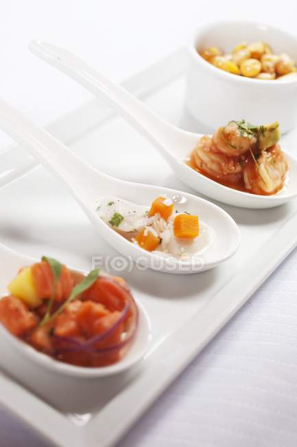 Vista de cerca de tres cucharadas de aperitivos de mariscos - foto de stock