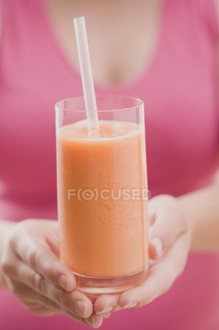 Femme tenant verre de smoothie à la mangue — Photo de stock