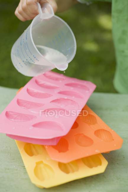 Hild pouring water into tray — Stock Photo
