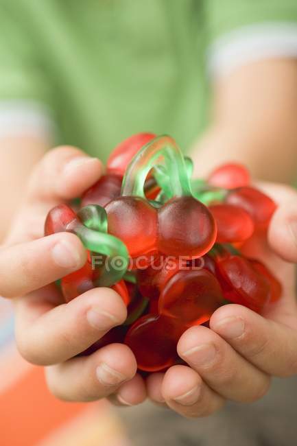 Hands holding cherry jelly sweets — Stock Photo