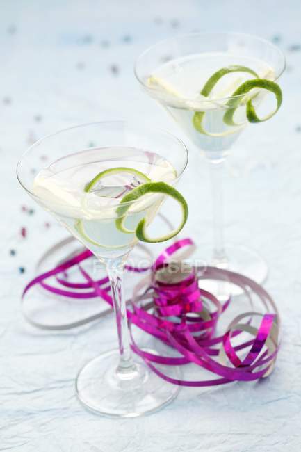 Closeup view of drinks with lime peels and colorful ribbons — Stock Photo