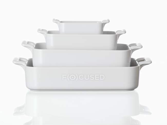 Closeup view of nested baking dishes on white surface — Stock Photo