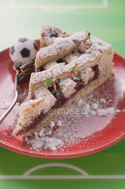 Piece of Linzer torte with football figurines — Stock Photo