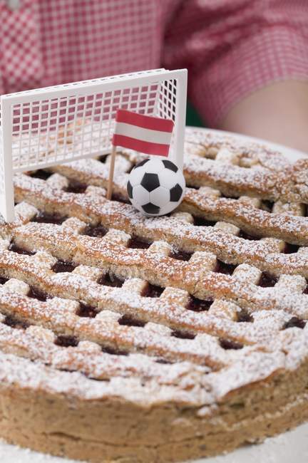 Крупним планом кадроване подання особи, яка займає Linzer торт з футболу, мета і австрійської прапор — стокове фото