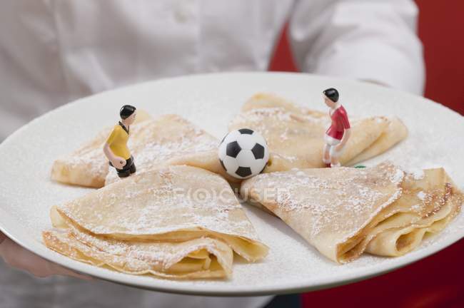 Cropped view of woman serving plate of sweet crepes with football figures — Stock Photo