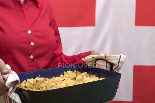 Woman serving cheese pasta bake — Stock Photo