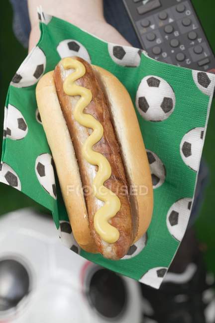Hand hält Hot Dog mit Senf — Stockfoto