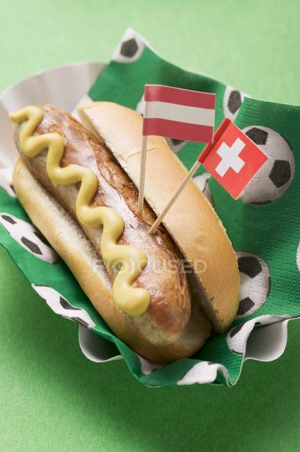Cachorro quente com mostarda e bandeiras — Fotografia de Stock